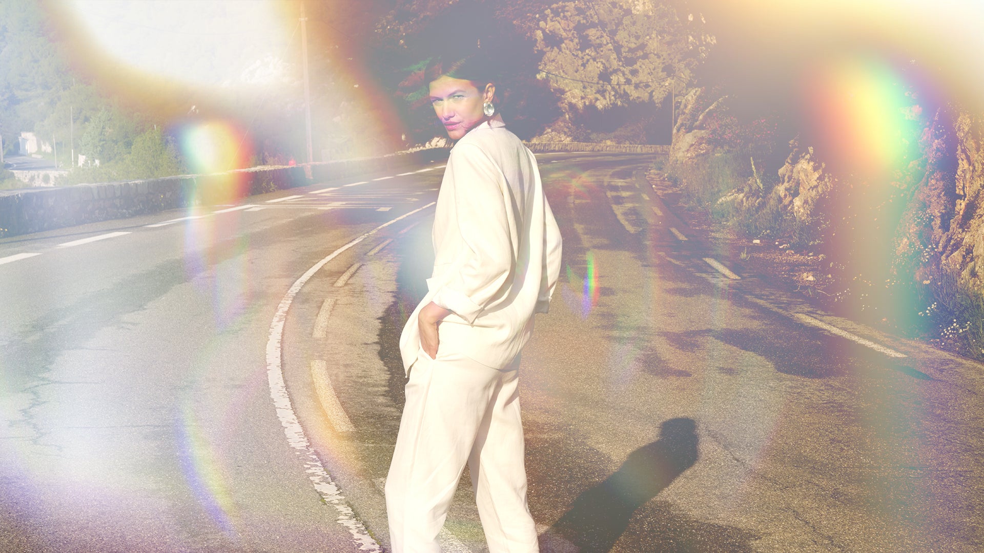 sustainable fashion, model walking in a white suit on an open road